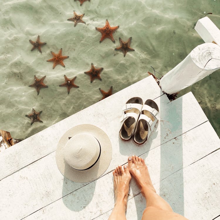 A Person's Feet Near A Hat