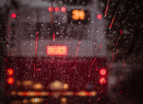 A cityscape view through a rain-streaked window at night, featuring blurred lights and bokeh effects.