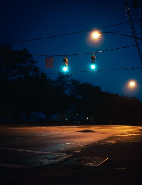 Free Serene nighttime street scene with glowing green traffic lights at an empty intersection. Stock Photo