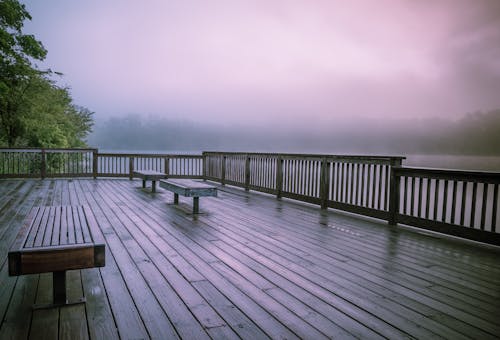 Benches on Wooden Terrace near Water in Fog