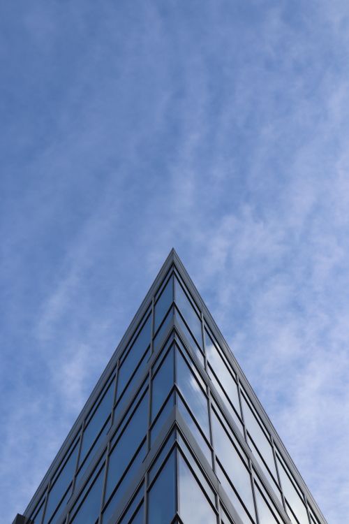 Free Low-angle view of a modern glass building with a clear blue sky background, capturing architectural elegance. Stock Photo