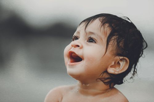 Free Close-up portrait of a happy wet-haired baby outdoors, showcasing joy and innocence. Stock Photo