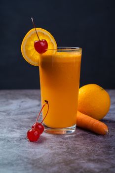 Healthy orange carrot juice garnished with cherries and an orange slice, perfect for a refreshing drink.