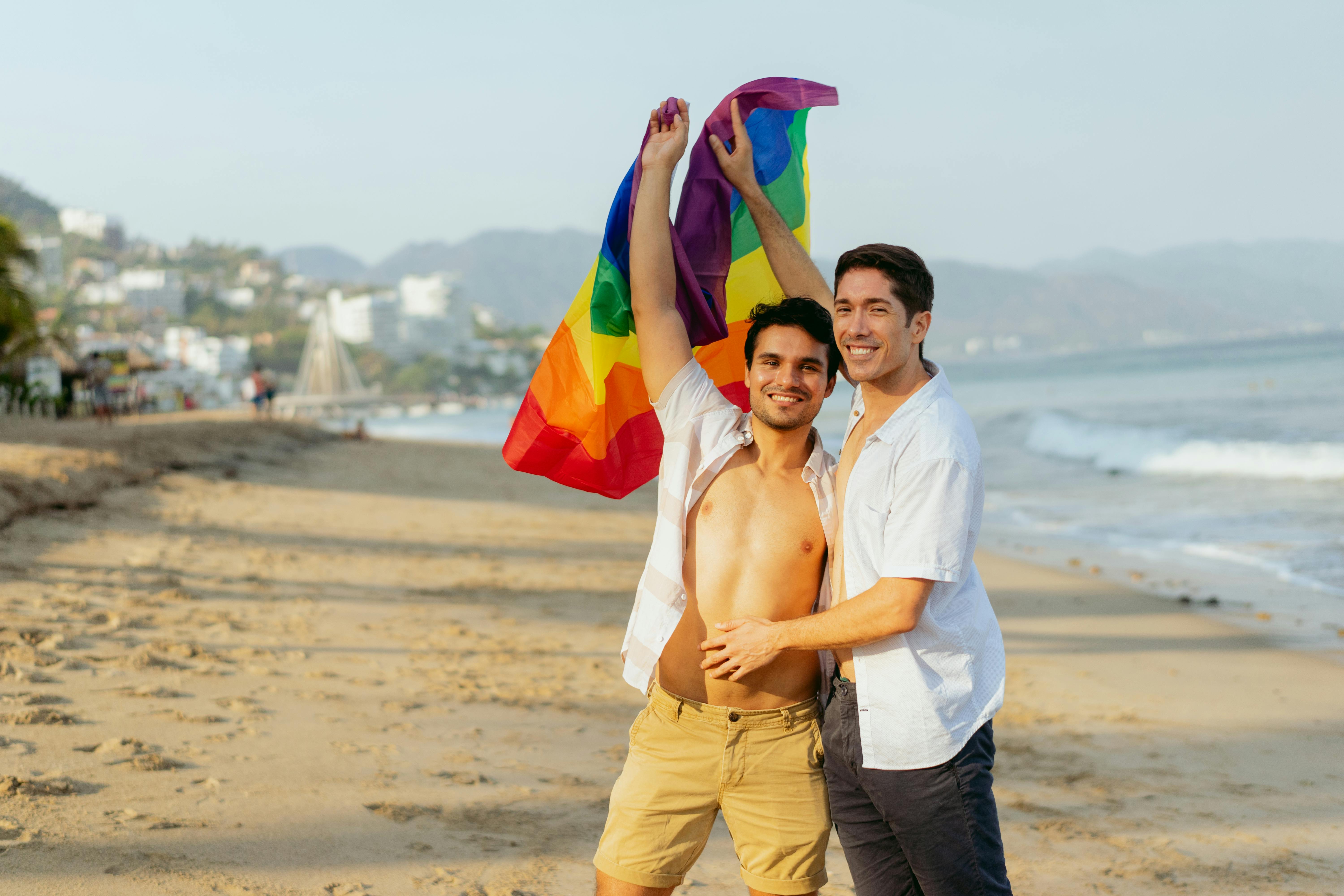 a couple holding a rainbow flag at the beach