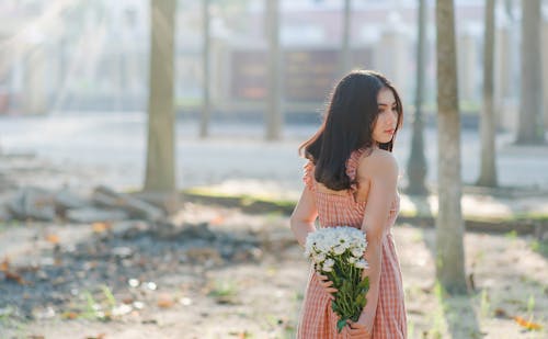 Kobieta Ubrana W Pomarańczową Sukienkę Bez Rękawów Trzyma Bukiet Kwiatów