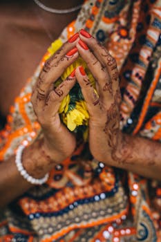 Close-up of henna-adorned hands holding marigolds, symbolizing Indian festivity and tradition.