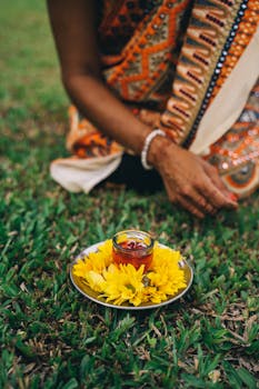 A serene Diwali setup with candle and yellow flowers on grass, India.