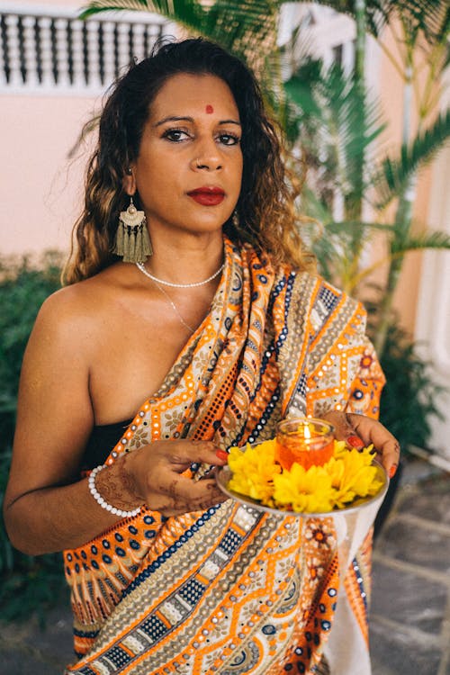 Woman in a Traditional Saree Dress Holding a Plate with Flowers and a Candle 