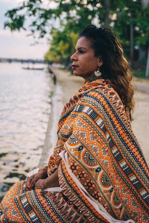 Woman in a Traditional Saree Dress Sitting by a Body of Water