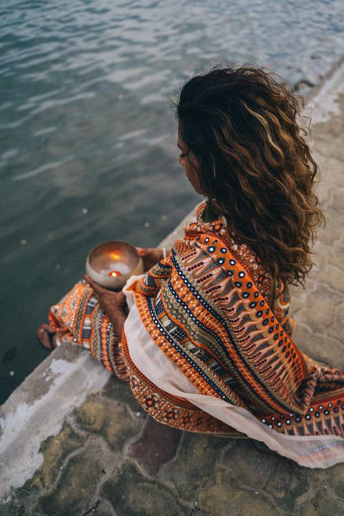 Woman in a Traditional Saree Dress Sitting by a Body of Water