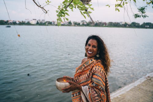 A Woman in Printed Saree Standing Near the Body of Water