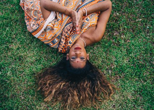 A Woman Lying on Green Grass Field with Her Hands Together