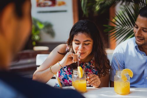 Free Group of friends enjoying orange juice and socializing outdoors in a sunny setting. Stock Photo