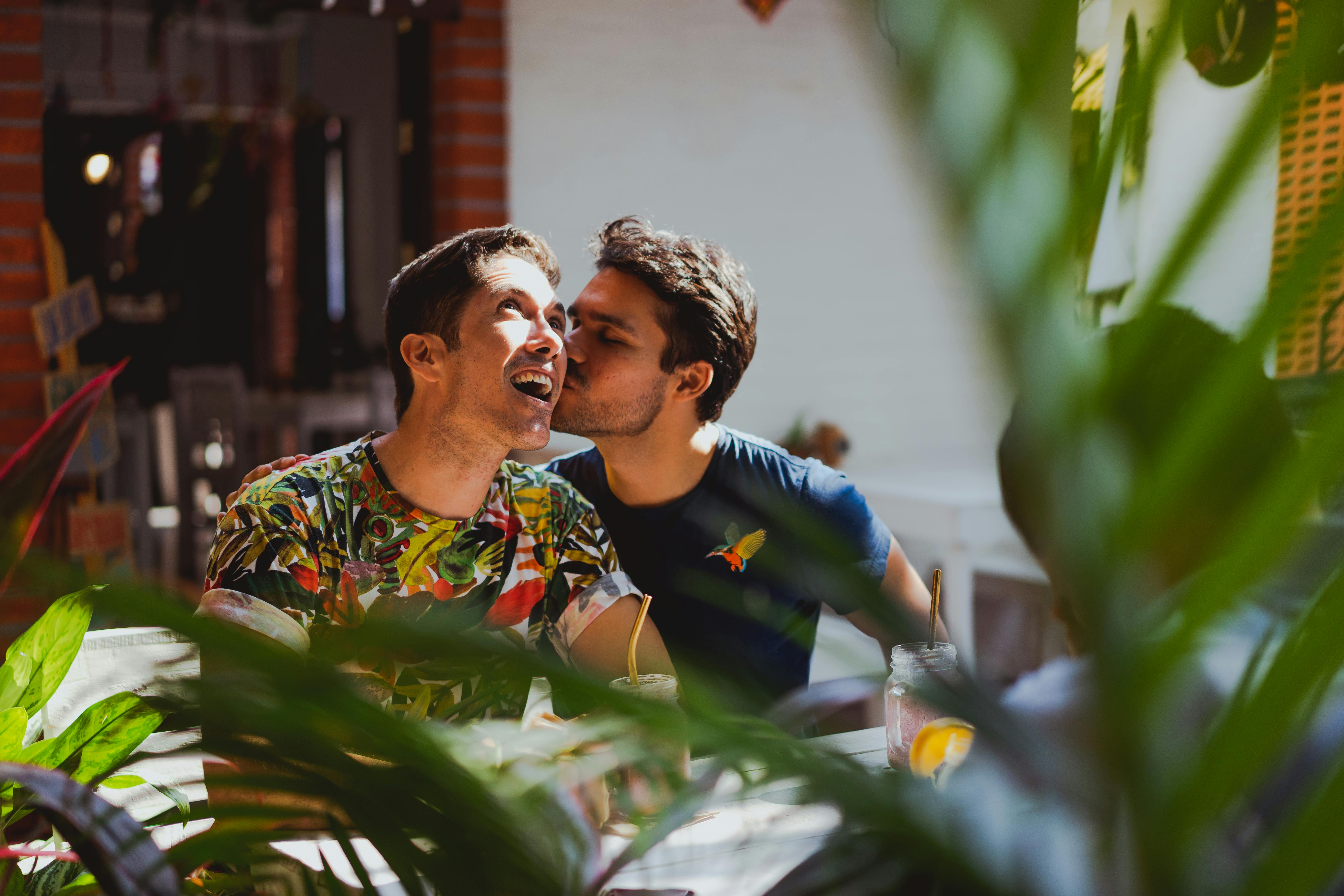 a man in blue shirt kissing his partner while looking up