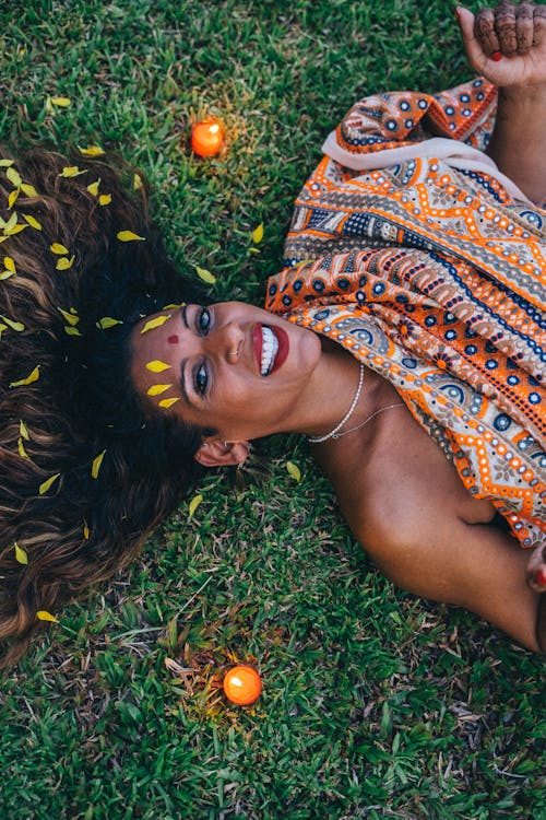 Free A Smiling Woman with Petals on Hair Lying on Grass  Stock Photo