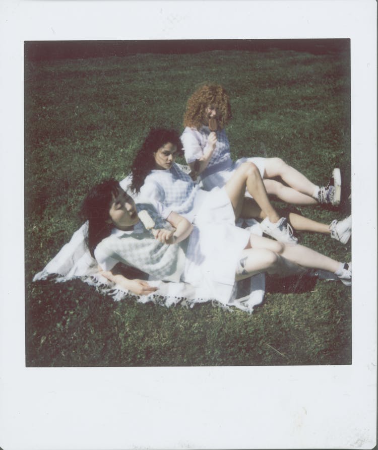 Polaroid Picture Of Women Eating Popsicles While Sitting On A Picnic Blanket