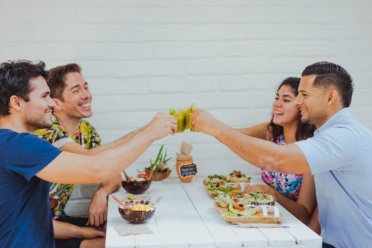 Group Of Friends Sitting At The Table In A Restaurant And Raising A Toast 