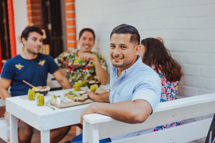 Group Of Friends Sitting At The Table In A Restaurant And Smiling 