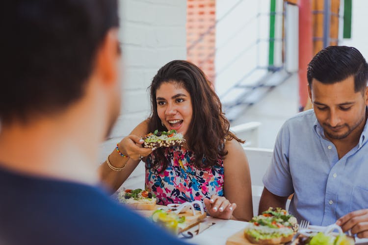 Friends Sitting At The Table In A Restaurant And Eating 