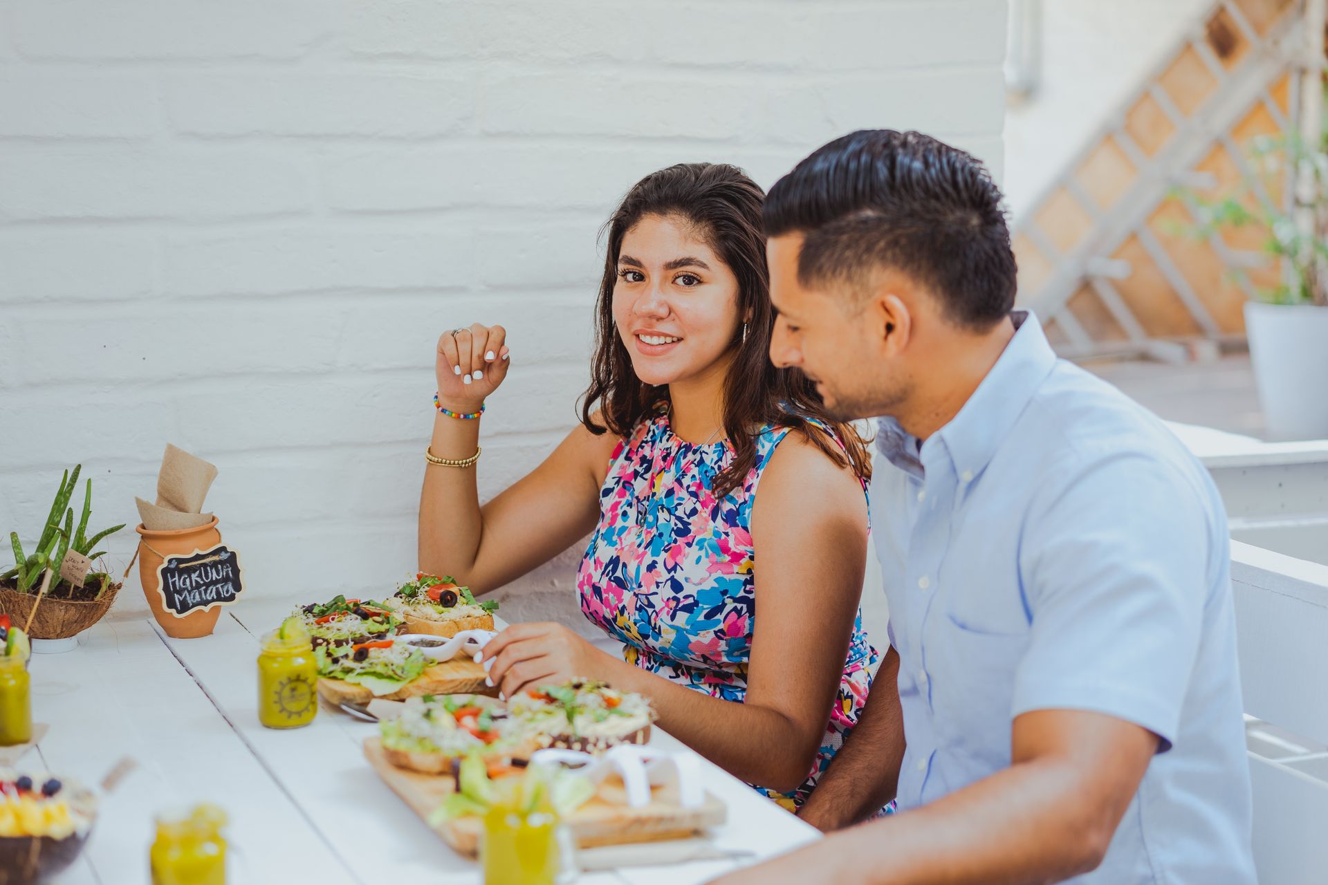 A couple shares a meal at an outdoor cafe with a bright, welcoming atmosphere.