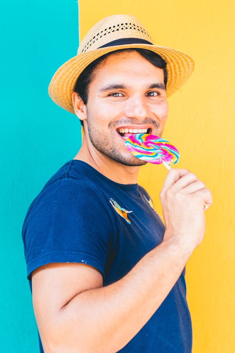 Photo Of A Man In A Blue Shirt Biting A Lollipop