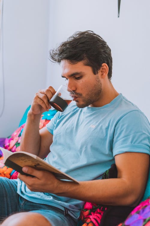 Free Man in Blue Shirt Drinking Coffee While Reading Stock Photo
