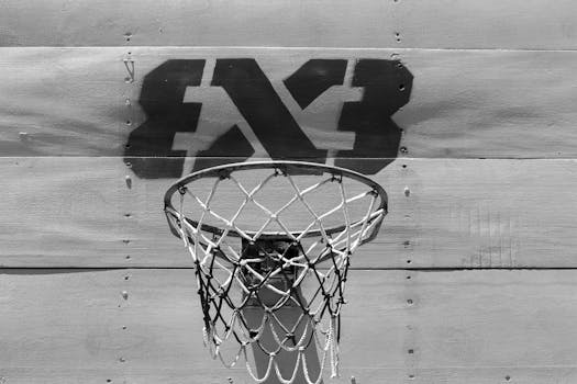 Monochrome image of a basketball hoop with a shadow on a wooden backboard.