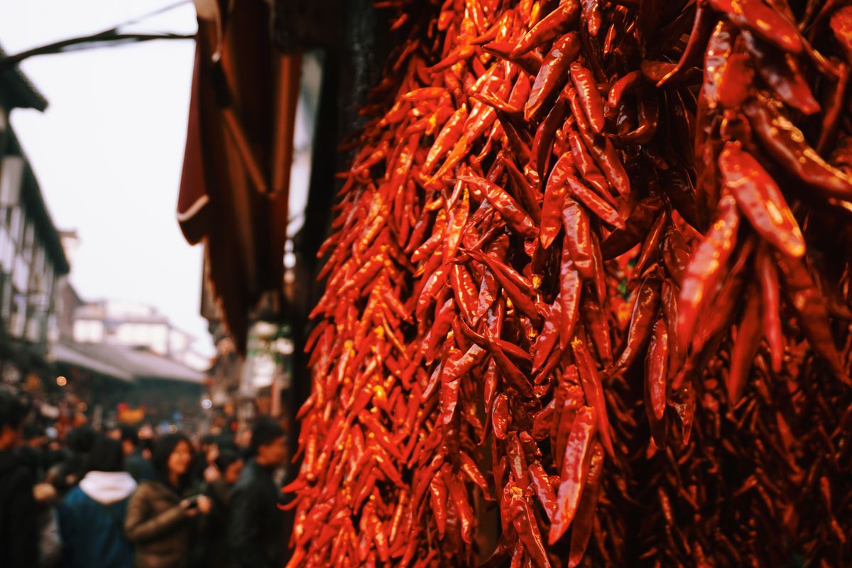 Kırmızı biberlerle dolu ahşap bir pazar tezgahı, Hot Pepper oyununu hatırlatan ateşli atmosfer