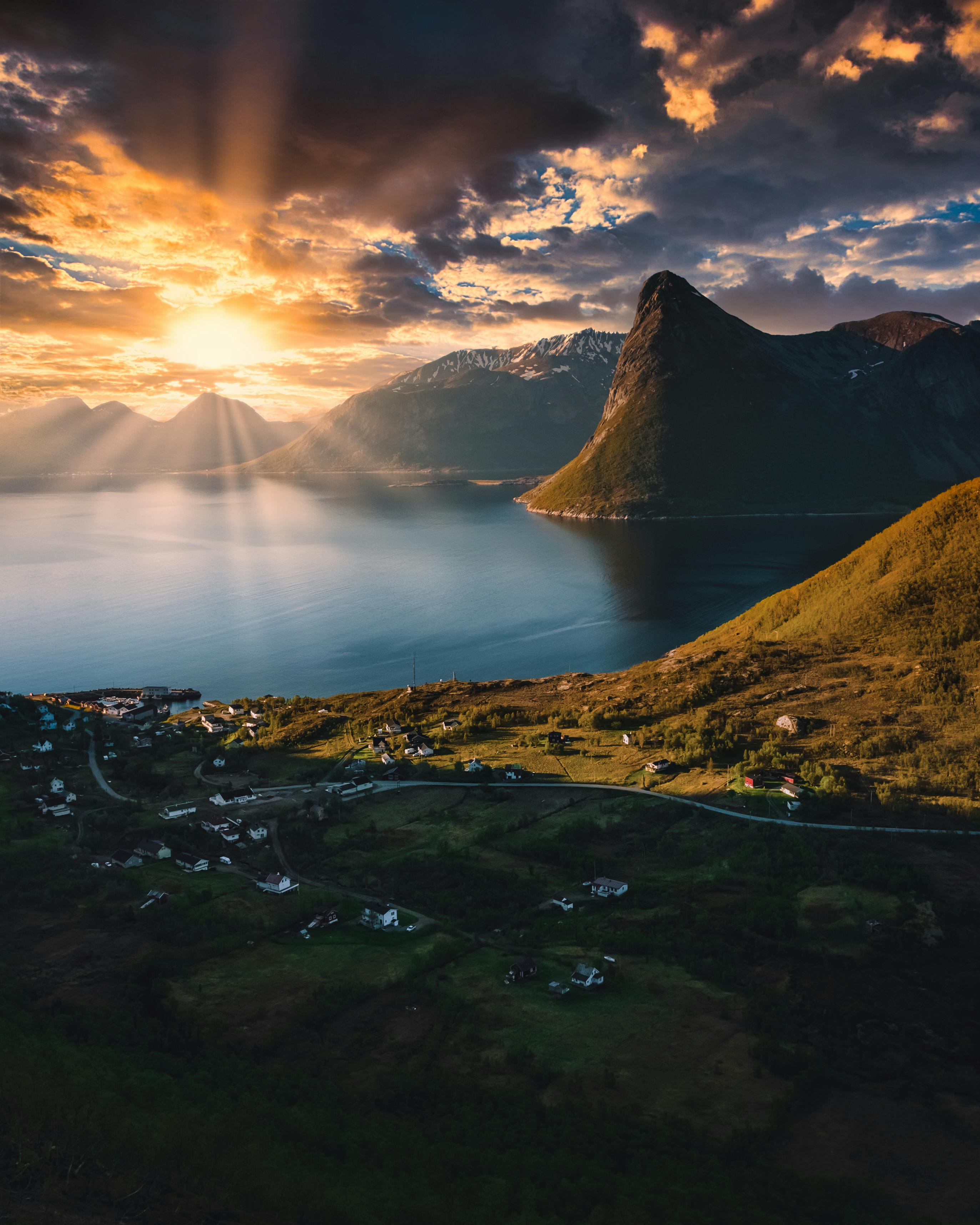 Breathtaking sunrise over a fjord in Troms og Finnmark, Norway, with stunning mountain silhouettes.