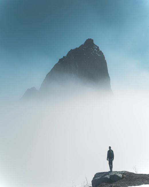 Silhouette of a man on a foggy mountain peak in Norway, capturing a serene and adventurous moment.