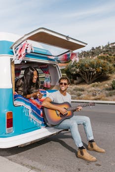 A joyful couple relaxes with guitar music near their retro camper van.