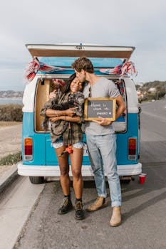 A couple shares a tender moment by their campervan on a sunny day.