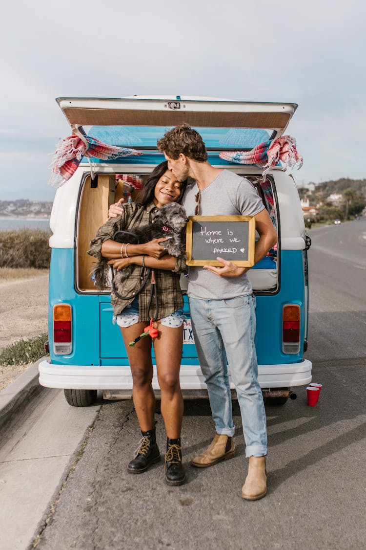 A Romantic Couple Kissing Beside A Campervan