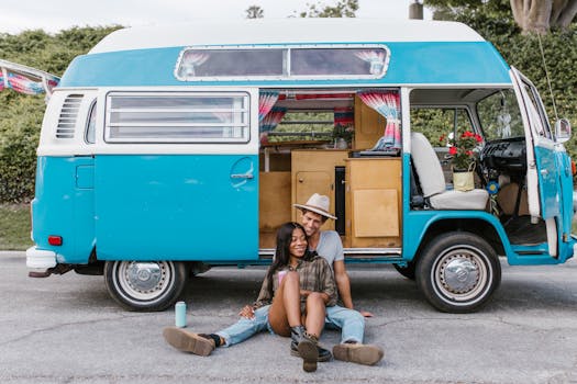 Happy couple sitting by a vintage blue van, embracing the joy of van life travel.
