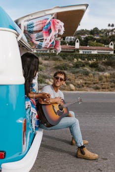 Couple enjoys a romantic moment on a road trip in a campervan with a guitar serenade.