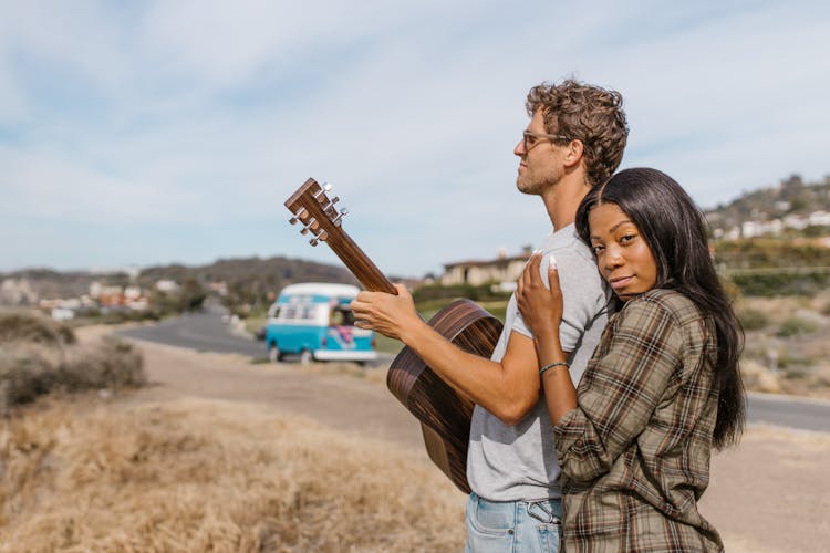 A Woman Holding A Man With A Guitar