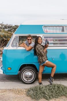 Smiling couple enjoying their adventure with a vintage blue campervan.
