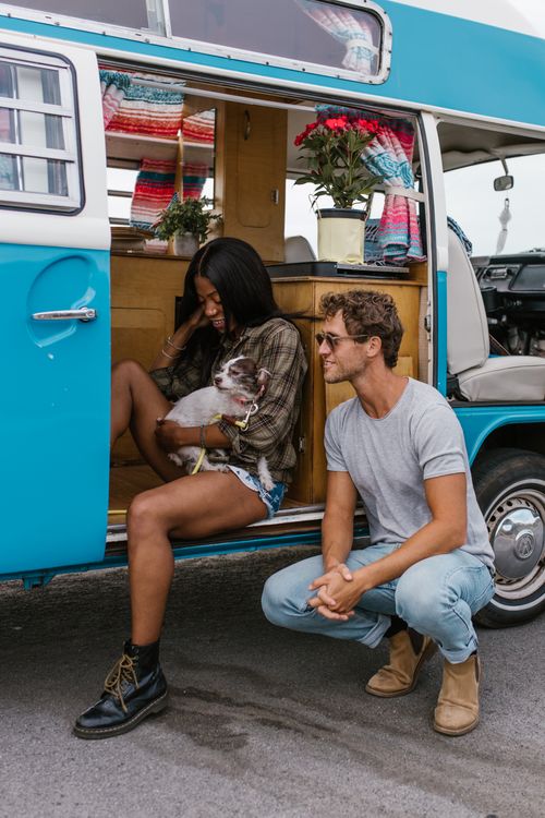 Free Couple with dog sitting by a retro van, embracing van life and companionship in an outdoor setting. Stock Photo