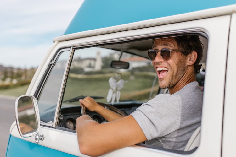 A Happy Man In Sunglasses Driving A Van