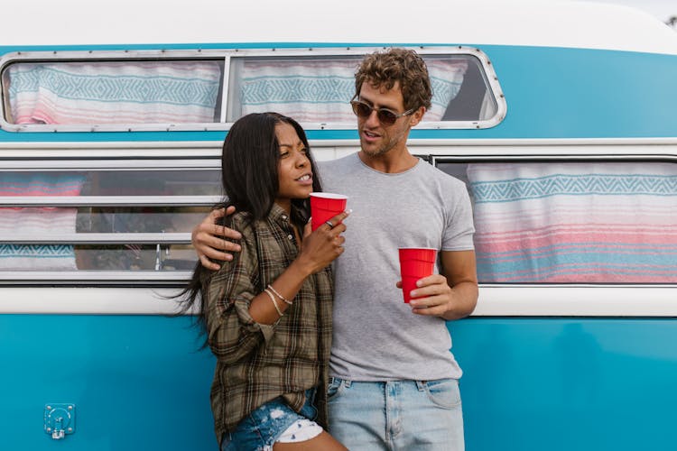 A Couple Standing Close Together Holding Disposable Cups 