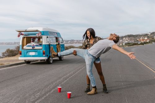 Free Couple having fun by a van on the road, capturing adventure and joy. Stock Photo