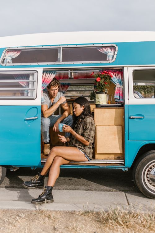 Free Couple enjoying a peaceful moment by a campervan during their road trip adventure. Stock Photo