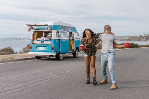 Free Young couple enjoying a carefree road trip by the seaside with a vintage van. Stock Photo