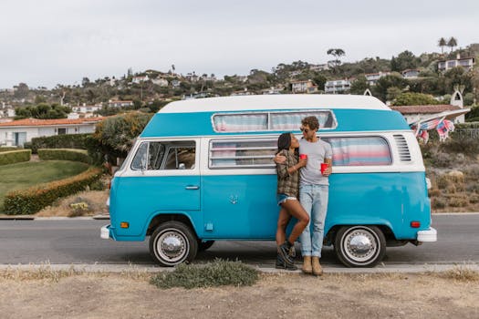 A couple enjoys a romantic moment by their campervan on a coastal road trip.