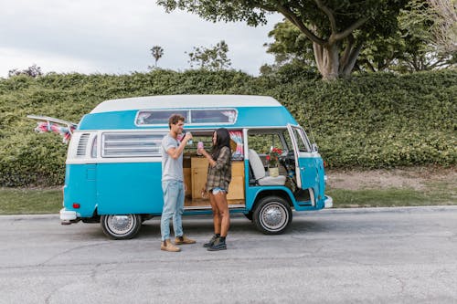 Couple Standing beside Their Campervan and Drinking 