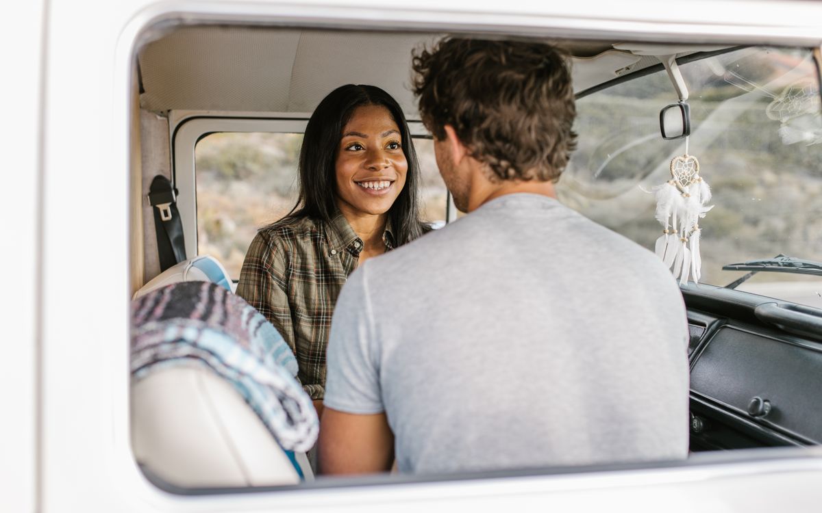 A smiling couple sits inside a van, creating joyful travel memories.