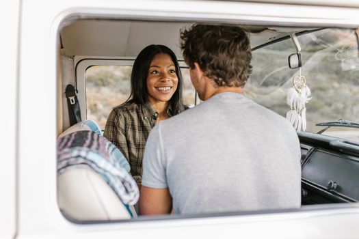 A smiling couple sits inside a van, creating joyful travel memories.