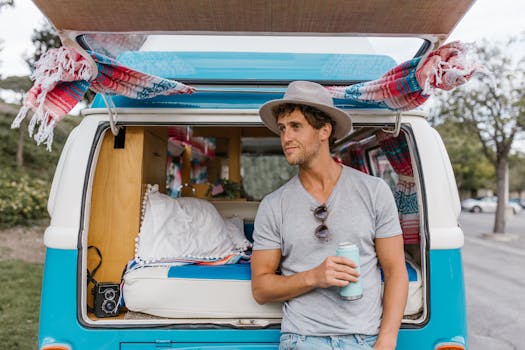 Man enjoying leisure time by a campervan, holding a drink, wearing a hat. Perfect travel lifestyle image.