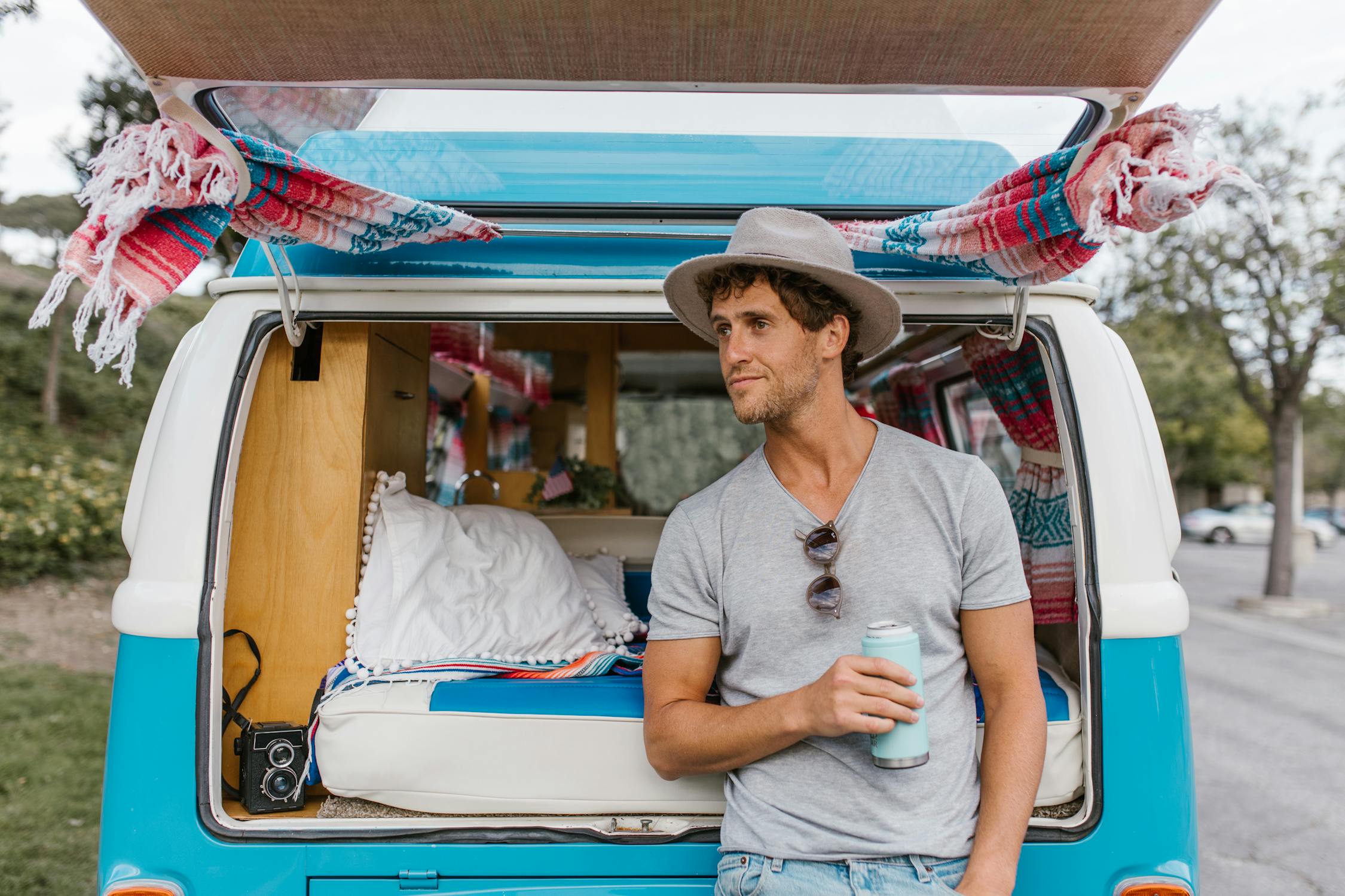 A Man Holding a Tumbler Standing at the Back of the Campervan