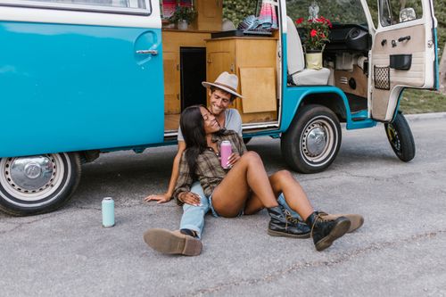 Free Happy couple enjoying a summer day by their retro campervan. Stock Photo